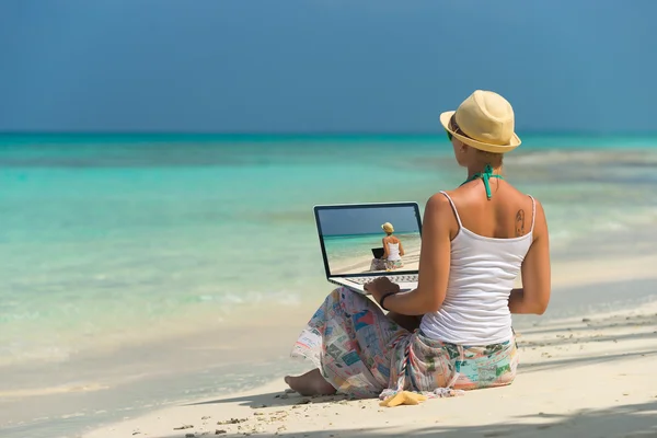 Kvinne på tropisk strand med bærbar datamaskin – stockfoto