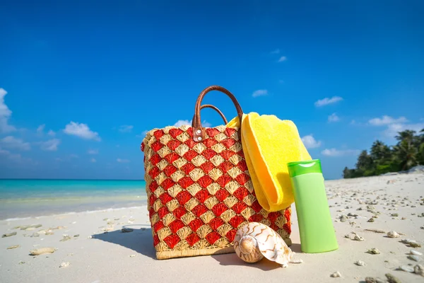 Summer beach bag with shell, towel on sandy beach — Stock Photo, Image