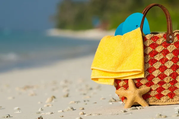 Summer beach bag with shell, towel on sandy beach — Stock Photo, Image