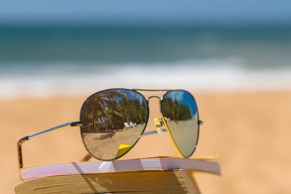 Knihy a sluneční brýle na pláži — Stock fotografie