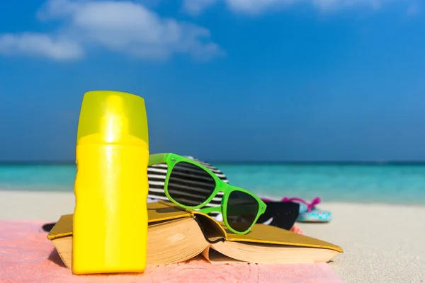 Écran solaire, chapeau et lunettes de soleil sur la plage tropicale — Photo