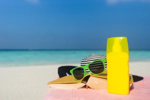 Sonnencreme, Hut und Sonnenbrille am tropischen Strand — Stockfoto