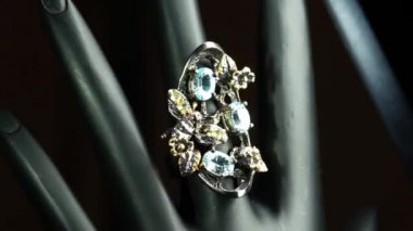 Gümüş yüzük ve siyah el üzerinde doğal değerli taşlar.