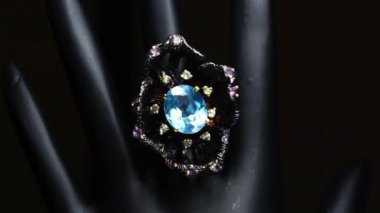 Gümüş yüzük ve siyah el üzerinde doğal değerli taşlar.