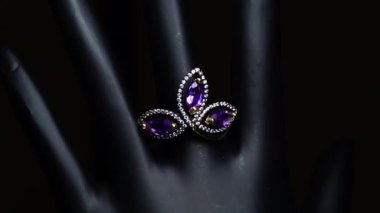 Gümüş yüzük ve siyah el üzerinde doğal değerli taşlar.