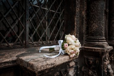 Kahverengi arkaplanda beyaz ve pembe güller olan gelin buketi. Metal ızgaradan bir arka planda gelin buketi