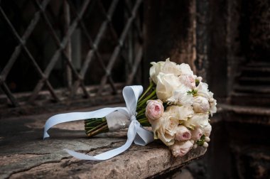 Kahverengi arkaplanda beyaz ve pembe güller olan gelin buketi. Metal ızgaradan bir arka planda gelin buketi