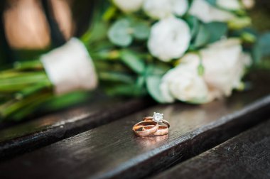 Gelinin buketinin arka planındaki ahşap tezgahta alyanslar.