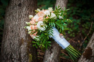 Gelinin buketinin arka planındaki ahşap tezgahta alyanslar.