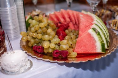 Düğün ziyafetinde meyve dilimleme. Karpuz, üzüm, çilek, portakal, erik, armut, dinha, şeftali, kivi, ananas, hurma, elma