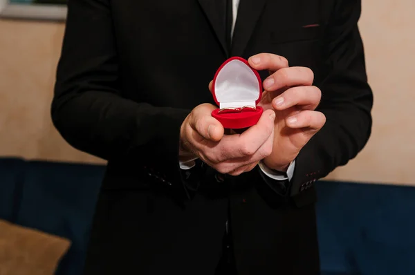 Wedding gold rings in a red box, wedding gold rings in the hands of the groom