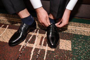 Adam siyah klasik ayakkabıların bağcıklarını bağlıyor. Damat güzel ayakkabılar giyer ve bağcıklarını bağlar.