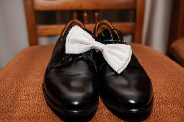 Kahverengi arka planda siyah klasik ayakkabılı beyaz papyon