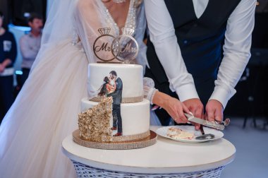 Yeni evliler düğün pastasını kesti. Düğündeki gelin ve damat düğün pastası kestiler.