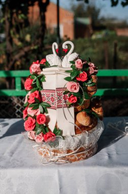 Çiçekler, hamur yaprakları ve kuğu heykelcikleriyle süslenmiş düğün ekmeği.