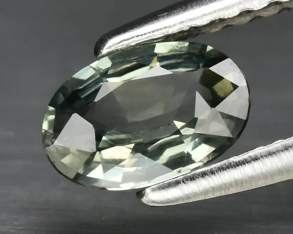 Natural gemstone green sapphire on gray background