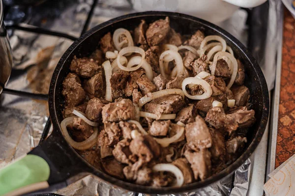 Fried veal liver with onions in a pan. Braised cow and pork liver