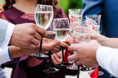 Glasses with white wine in the hands of the newlyweds