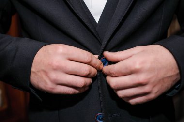 Adam ceketine bir düğme takıyor. Damat ceketine bir düğme takar.