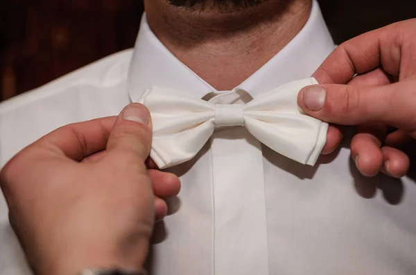 White bow tie in the hands of the groom. Bow tie in the hands of a man