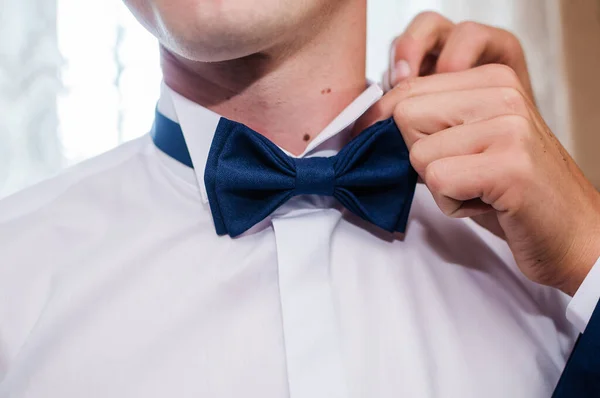 Blue bow tie in the hands of the groom. Bow tie in the hands of a man