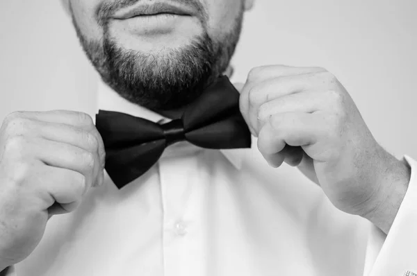 Blue bow tie in the hands of the groom. Bow tie in the hands of a man