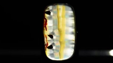 Siyah arkaplandaki twezzerlarda doğal iris agatı