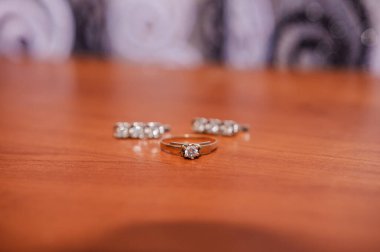 Küpeler, altın bir yüzük ve kahverengi bir arka plan.