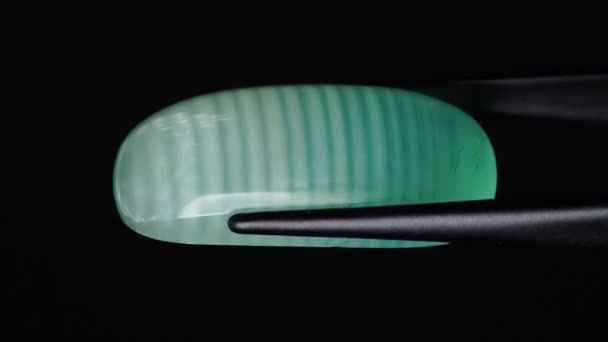 Natural green calcite in the tweezers on the turning table — Stock Video