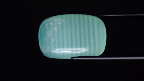 Natural green calcite in the tweezers on the turning table — Stock Video