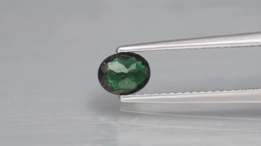 Sehpanın üzerindeki cımbızda doğal yeşil turmalin.