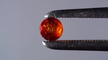 Dönme masadaki cımbızda doğal kahverengi yakut taşı var.