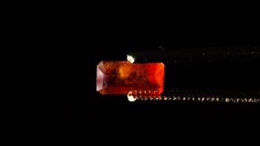 Dönme masadaki cımbızda doğal kahverengi yakut taşı var.