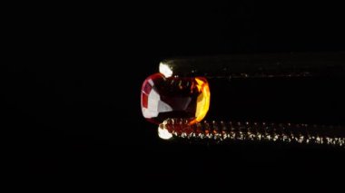 Dönme masadaki cımbızda doğal kahverengi yakut taşı var.