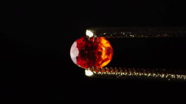 Dönme masadaki cımbızda doğal kahverengi yakut taşı var.