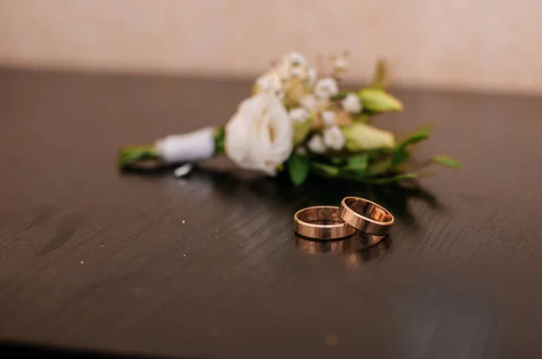 Sepasang Cincin Pernikahan Dan Boutonniere Pengantin Pria Pada Latar Belakang — Stok Foto