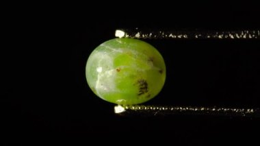 Doğal hidrogrossular yeşil kehribar cımbızla sehpanın üzerinde