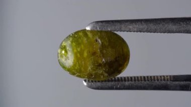 Doğal hidrogrossular yeşil kehribar cımbızla sehpanın üzerinde
