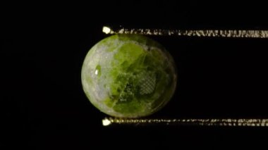 Doğal hidrogrossular yeşil kehribar cımbızla sehpanın üzerinde