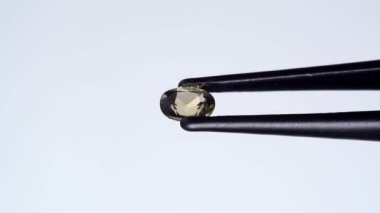 Doğal yeşil kornerupin mücevheri sehpanın üzerinde cımbızla