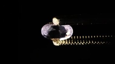 Sehpanın üzerinde cımbızla doğal morganit mücevheri