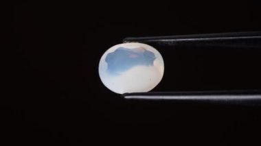 Arka plandaki cımbızda doğal opal değerli taş