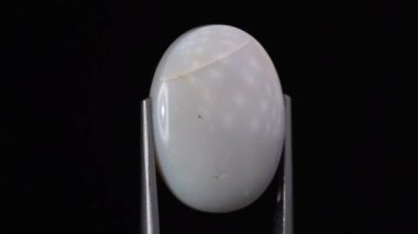 Arka plandaki cımbızda doğal opal değerli taş