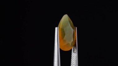 Arka plandaki cımbızda doğal opal değerli taş