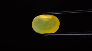 Arka plandaki cımbızda doğal opal değerli taş