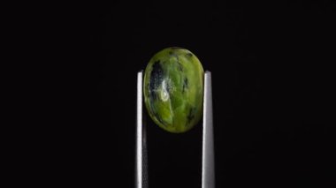 Arka plandaki cımbızda doğal yeşil opal değerli taş