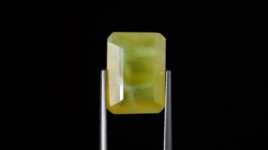 Arka plandaki cımbızda doğal sarı ateş opal taşı