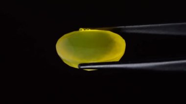 Arka plandaki cımbızda doğal sarı ateş opal taşı