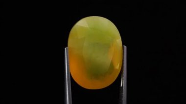 Arka plandaki cımbızda doğal sarı ateş opal taşı