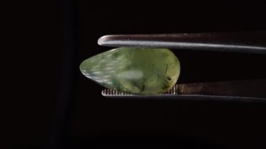 Arka plandaki cımbızda doğal yeşil taş var.